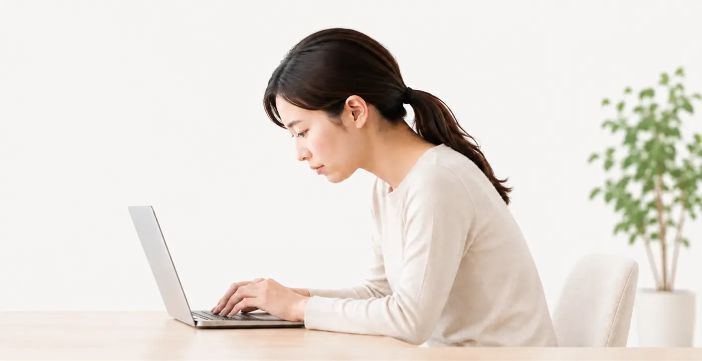 パソコン作業中に背中が丸くなっている女性